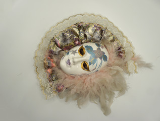 Vintage female porcelain venetian mask with delicate feathers and painted decorations.