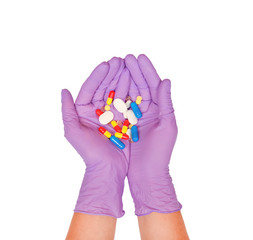 Palms in purple latex gloves hold a handful of pills