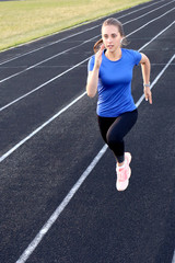Fototapeta na wymiar Runner athlete running on athletic track training her cardio in stadium. Jogging at fast pace for competition
