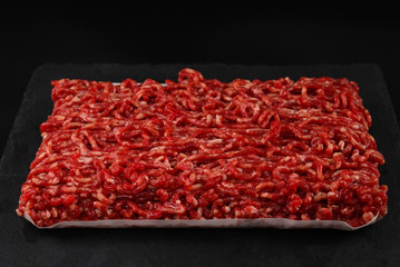 Chopped raw meat  on a black  background.