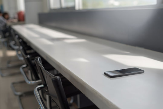 Smart Phone Place On Table In Public Library In Selective Focus, Concept : Forget / Lost.