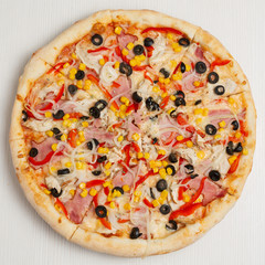 Italian pizza with corn, sweet pepper and olives, on a wooden board