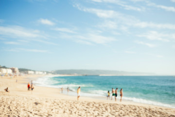 Fototapeta na wymiar Blurred beach with people and ocean waves. Summer background.