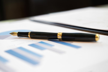 Office desk with pen on business charts and graphs. Business concept.