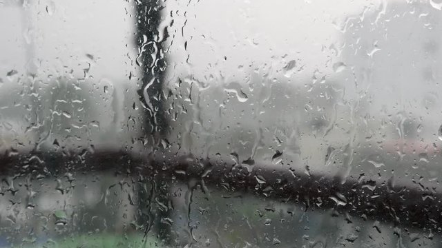 Strong rain water flushes against window glass and streaming down, close up. Raindrops on glass background in rainy season. 4k