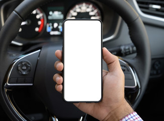 Hand holding blank screen of smartphone while driving car.
