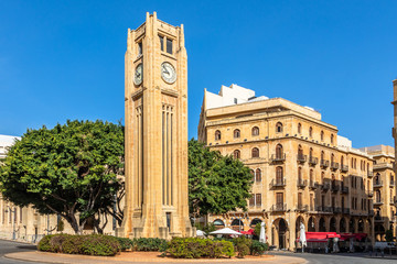 Naklejka premium Wieża zegarowa na placu Al-Abed Nejmeh z drzewami i budynkami dookoła, Bejrut, Liban
