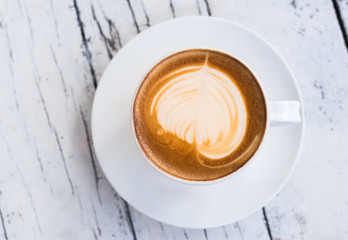 Top view a cup of latte art coffee on white wooden table
