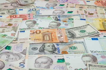 Money and finances concept. One hundred dollar new bill on colorful abstract background of Ukrainian, American and euro national currency banknotes