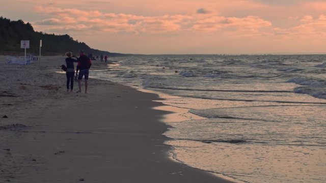 People relaxing on the beach of Baltic Sea at sunset.