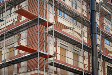 Fototapeta premium Metal scaffolding around red brick old building