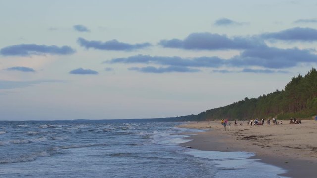 People relaxing on the beach of Baltic Sea at sunset.