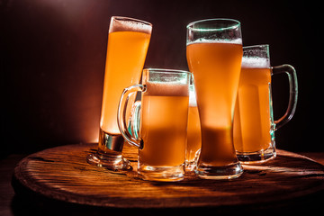 Creative concept. Beer glasses on wooden table at dark toned foggy background.