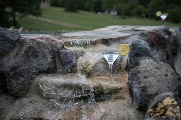 Glass of martini cocktail at swimming pool with ocean and palm tree background. A glass of blue martini cocktail welcome drink bar.Selective focus. season and holidays concept.