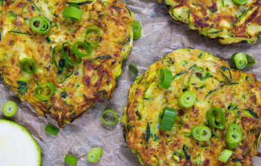 Zucchini pancakes with chives on a wooden table.