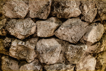 Close-up of a wall of dirty old stones.