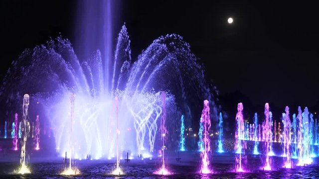 Fountain illuminated at full moon night in city park