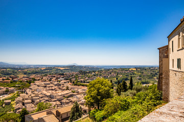 Fototapeta na wymiar The ancient and beautiful city of Amelia, in Umbria, seen from above. The view of the green Umbrian hills. The mountains in the background. The rich vegetation, the streets and the roofs of the houses