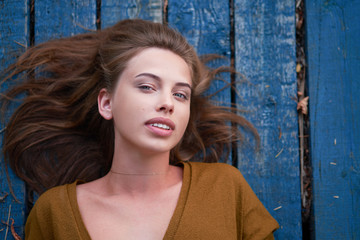 Fototapeta premium Beautiful caucasian young woman Lying on her back on wooden background.