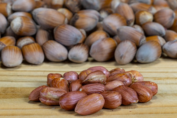 Shelled hazelnuts on the background of unshelled nuts on the wooden board