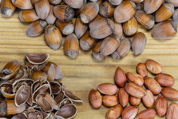 Shelled hazelnuts with unshelled nuts and nut-shells on the wooden board