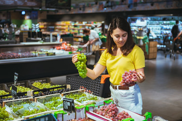 woman buying grapes in store