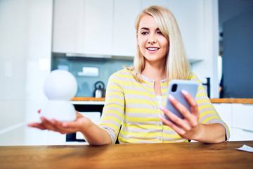 Portrait of young woman setting up home secuity system through mobile app at home