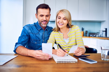 happy couple lmanaging home finances, looking at bills