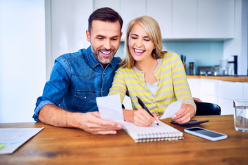 Portrait of happy couple looking at bills while managing home finances
