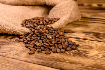 Sackcloth and scattered coffee beans on wooden table