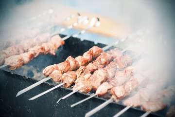 Appetizing portions of shish kebab, strung on skewers, are fried from the heat of the coals in the grill, which emit thick smoke.