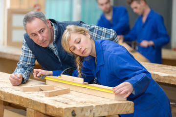 carpenter with female apprentice in workshop