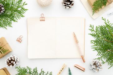 Flat lay Christmas frame made of fir branches, festive decorations, Christmas balls on white background. Blank notepad for 2020 to do list with copy space