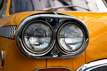 Headlight of an old yellow retro car, close-up