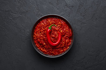 Schezwan Sauce in black bowl at dark background. Schezwan Sauce is Indo-chinese or Sichuan cuisine hot sauce with red chilli, garlic and ginger.