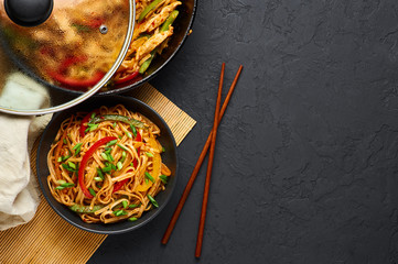 Vegetarian Schezwan Noodles or Vegetable Hakka Noodles or Chow Mein in black bowl at dark background. Indo-chinese cuisine hot dish with udon noodles, vegetables and chilli sauce. Copy space