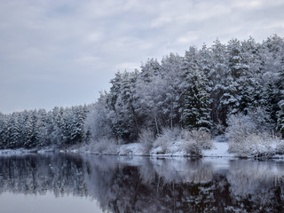 view of beautiful river winter day, snowy trees, many clouds, beautiful reflections, calm river water, Gauja river, Valmiera, Latvia
