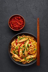 Chicken Schezwan Noodles or Hakka or Chow Mein in black bowl at dark background. Schezwan Noodles is indo-chinese cuisine hot dish with udon noodles, vegetables and chilli sauce or Schezwan sauce