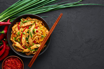 Chicken Schezwan Noodles or Hakka or Chow Mein in black bowl at dark background. Schezwan Noodles is indo-chinese cuisine hot dish with udon noodles, vegetables and chilli sauce. Copy space