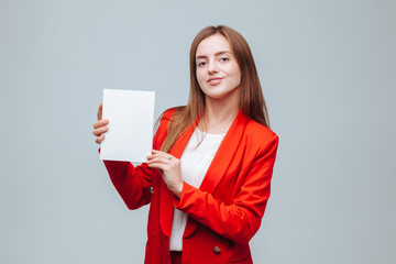 girl in a red jacket holds a presentation of the book on a gray background