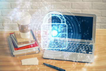 Double exposure of desktop with computer and lock icon hologram. Concept of data safety.