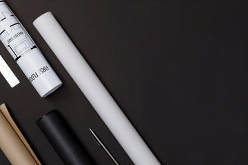 Creative flat lay of architects black table with roll blueprints, architectural project plan, engineering tools and office supplies, Workspace for new designer concept, Top view with copy space