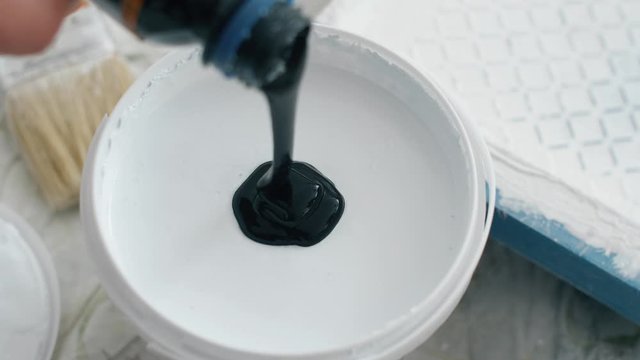 Black paint pouring in white paint for painting walls. Coloring paints for repair. 4k slow motion footage.