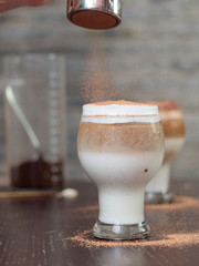 Cup of cold drink made by milk, coffee and cream, covered with coco powder.