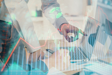 Double exposure of chart with businessman typing on computer in office on background. Concept of...