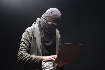Terrorist with laptop on black background
