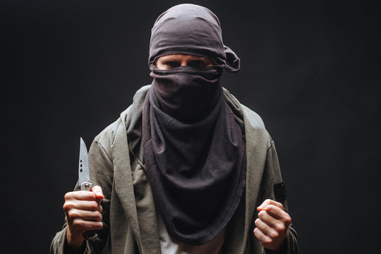  criminal in a mask threatens with a knife the dark background