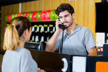 man on the phone while talking to bowling customer