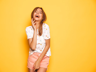 Obraz premium Portrait of young beautiful smiling hipster girl in trendy summer jeans shorts clothes. Sexy carefree woman posing near yellow wall in studio. Positive model having fun