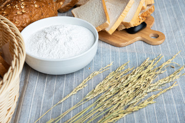 slide white bread ,whole wheat with whole grain bread and white blow of flour on light blue floor with some fresh wheat.